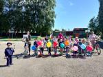 Дети на велосипедах и самокатах украшенных шарами и флажками, выстроились на территории детского сада.